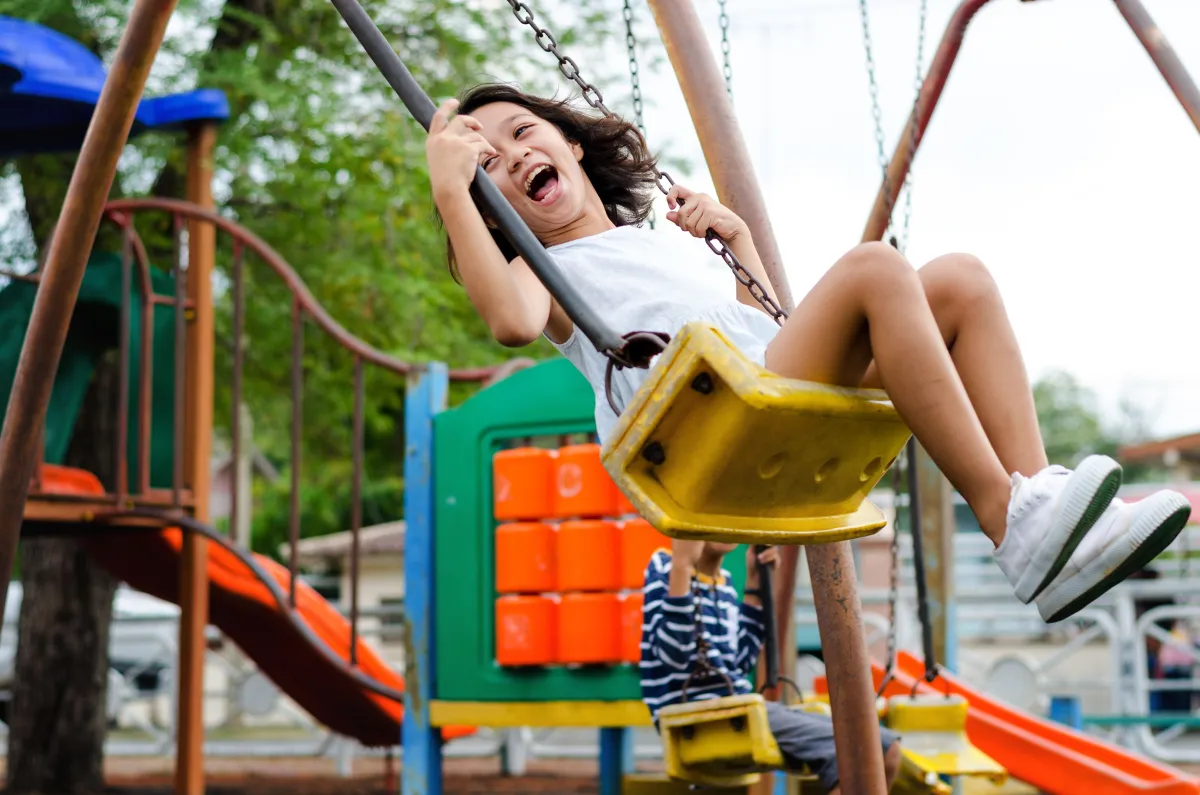 Child laughing on a swing at the Balaji Classica kids play area