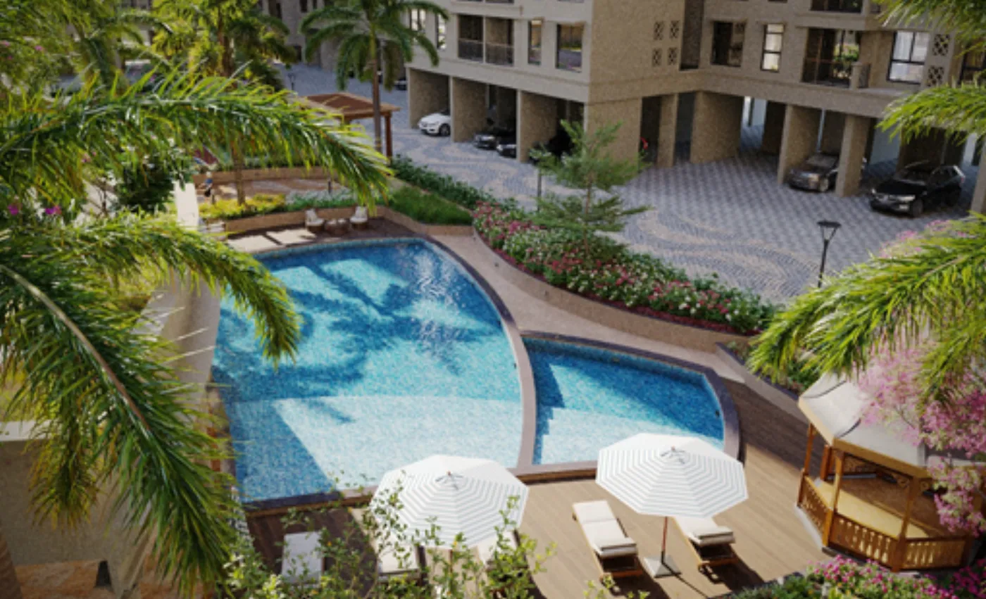 Landscaped swimming pool and sun deck framed by palms inside the gated Balaji Classica campus